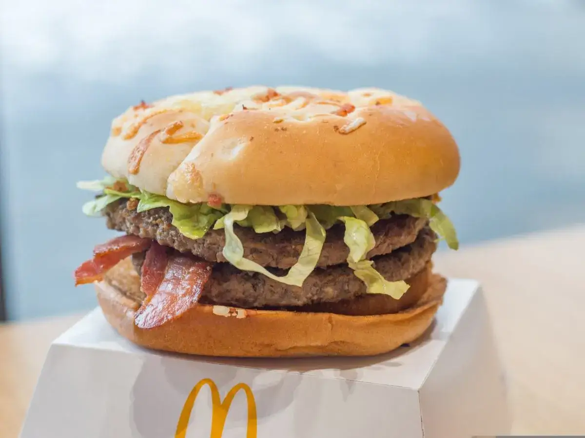 Drwal z kurczakiem, czyli soczysty burger z dwoma kotletami wołowymi, chrupiącym boczkiem i świeżą sałatą, na białym opakowaniu McDonald's.